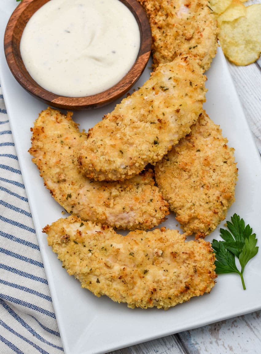 air fryer ranch chicken tenders on a white serving platter with a small bowl of ranch dressing on the side for dipping