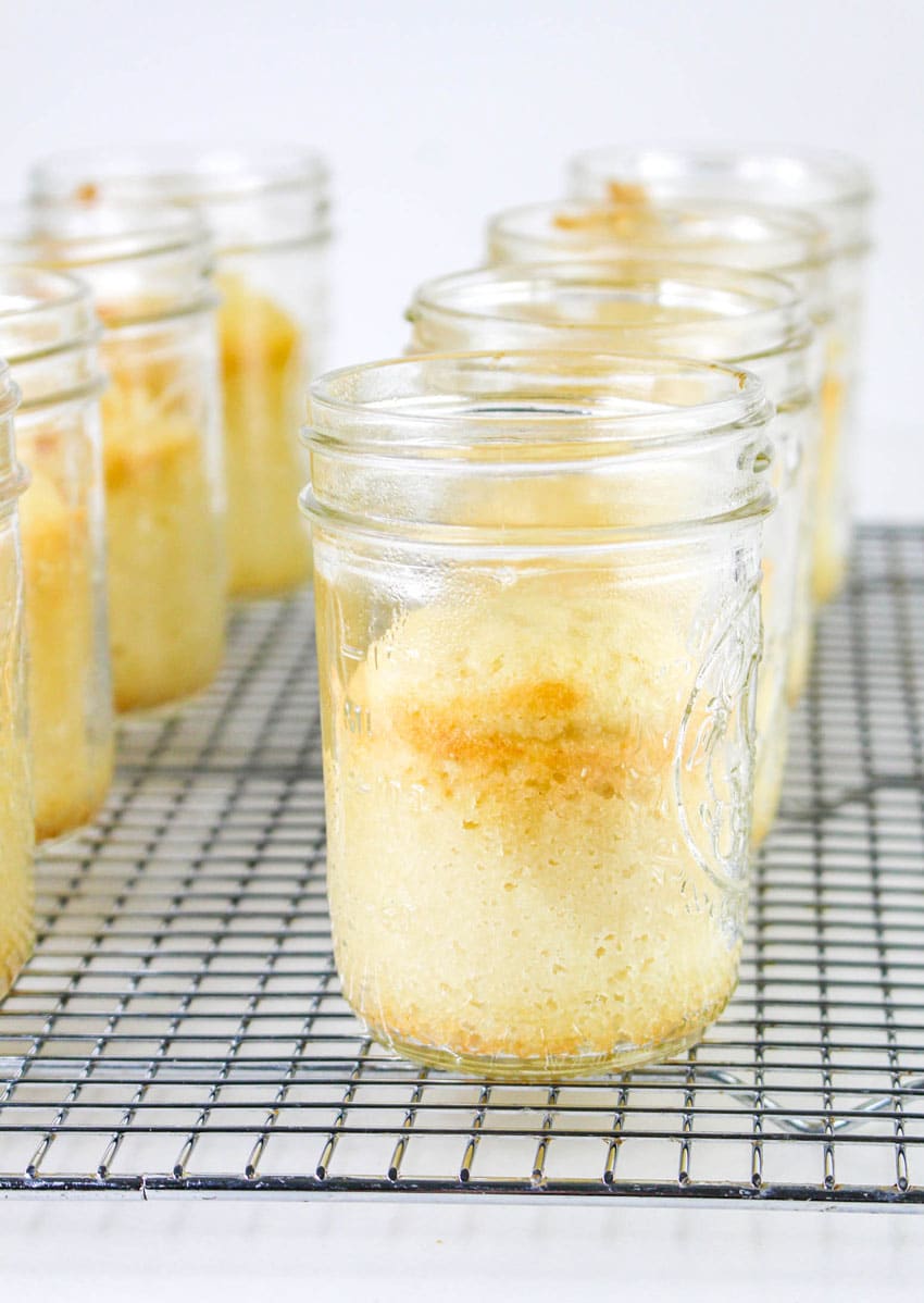 baked mini cakes in jars resting on a metal cooling rack