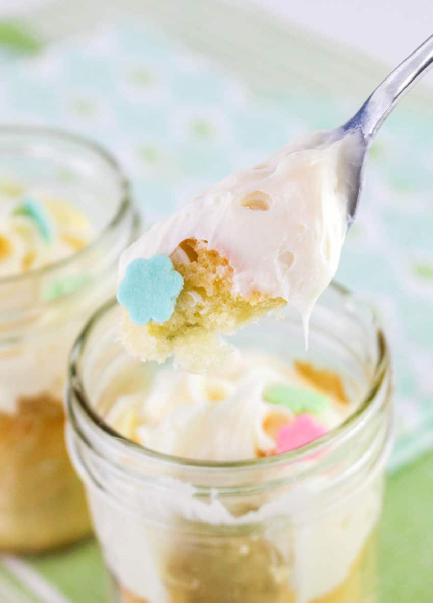a silver fork holding up a scoop of a frosted cake in a jar
