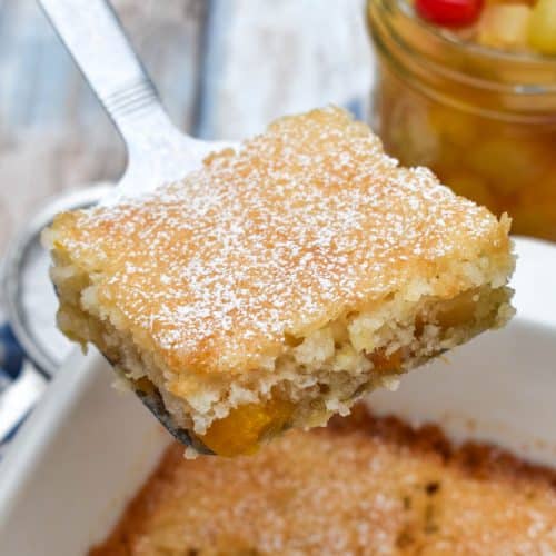 a silver spatula holding up a slice of fruit cocktail cake