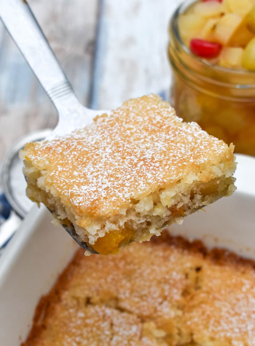 a silver spatula holding up a slice of fruit cocktail cake