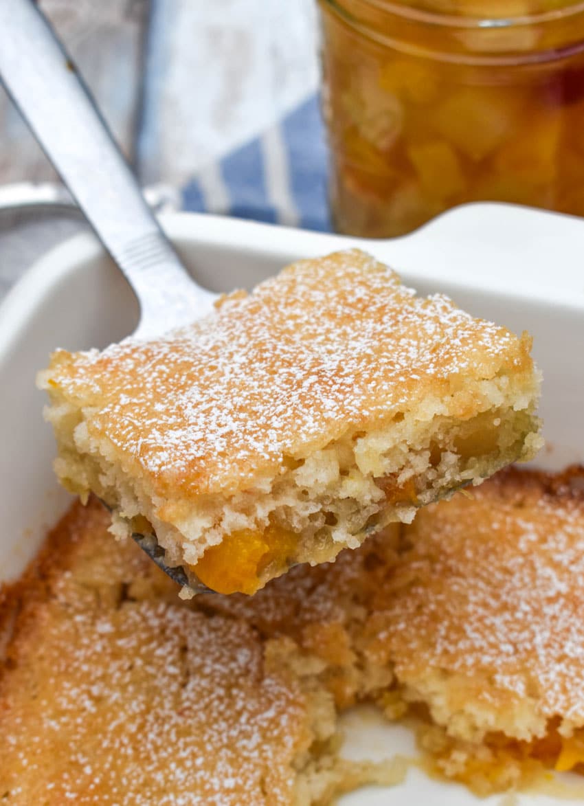 a silver spatula holding up a slice of fruit cocktail cake