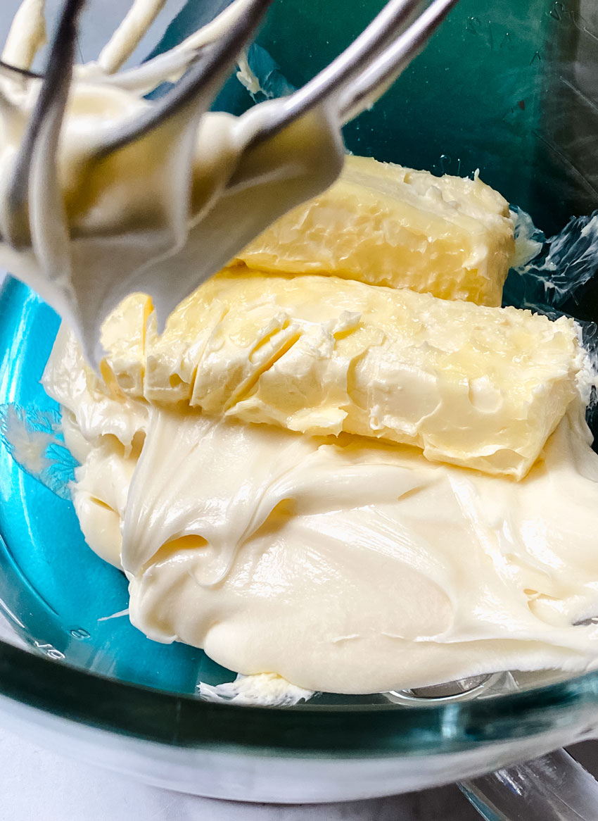 softened sticks of butter and canned frosting in the bowl of a stand mixer