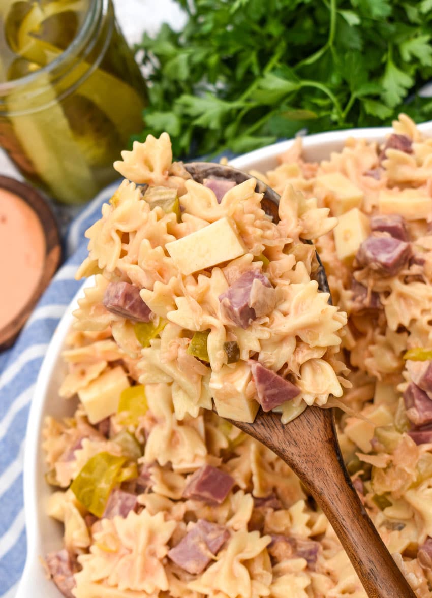 a wooden spoon holding up a scoop of rueben pasta salad