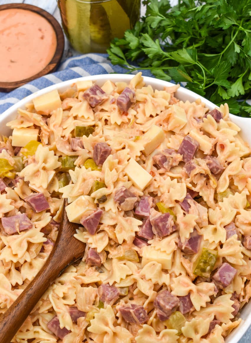 a wooden spoon scooping rueben pasta salad out of a large white serving bowl