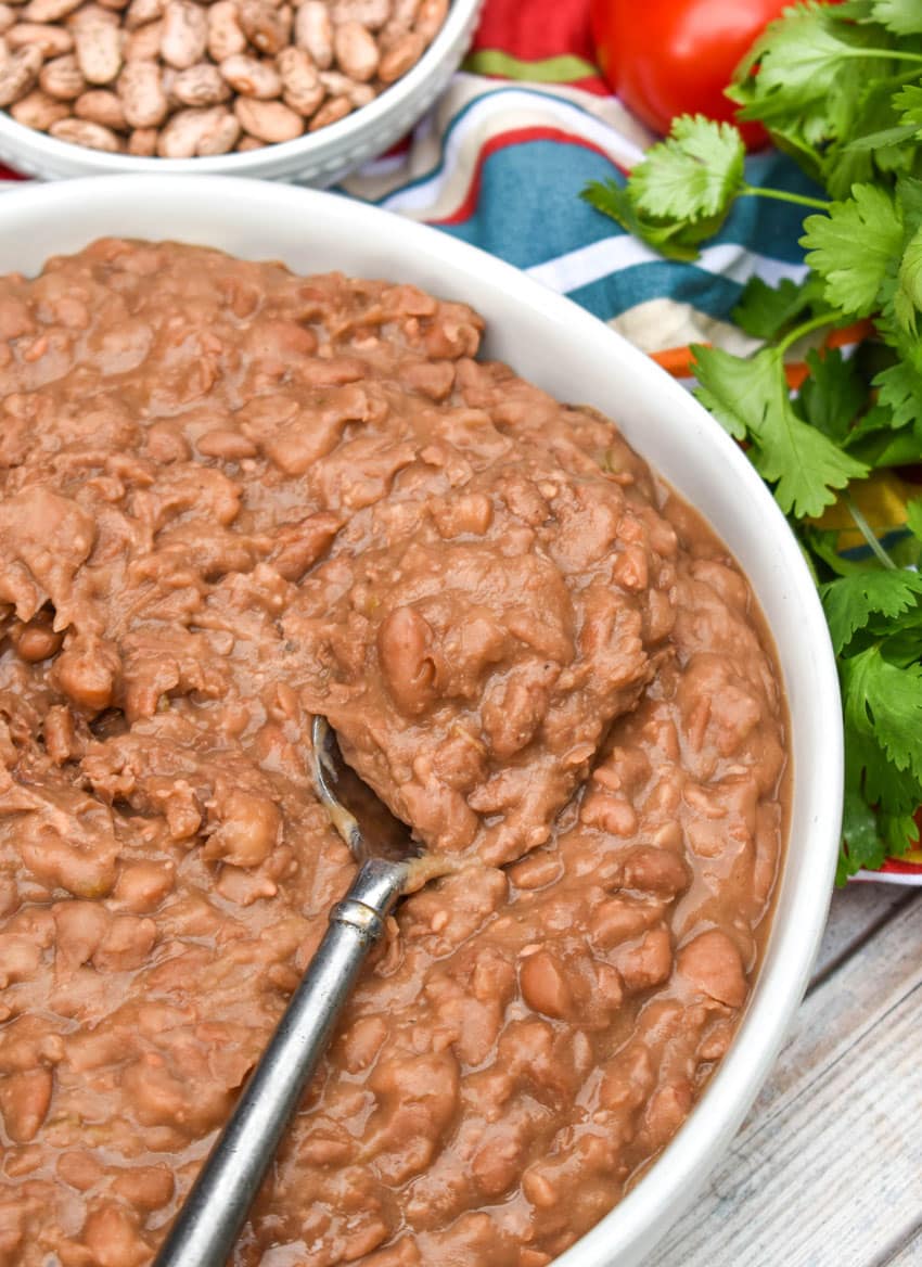 slow cooker refried beans in a shallow white serving bowl