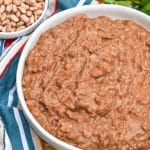 slow cooker refried beans in a shallow white serving bowl