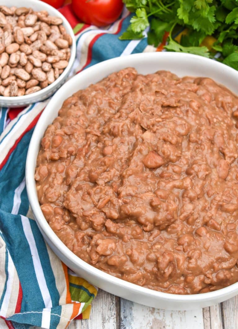 slow cooker refried beans in a shallow white serving bowl
