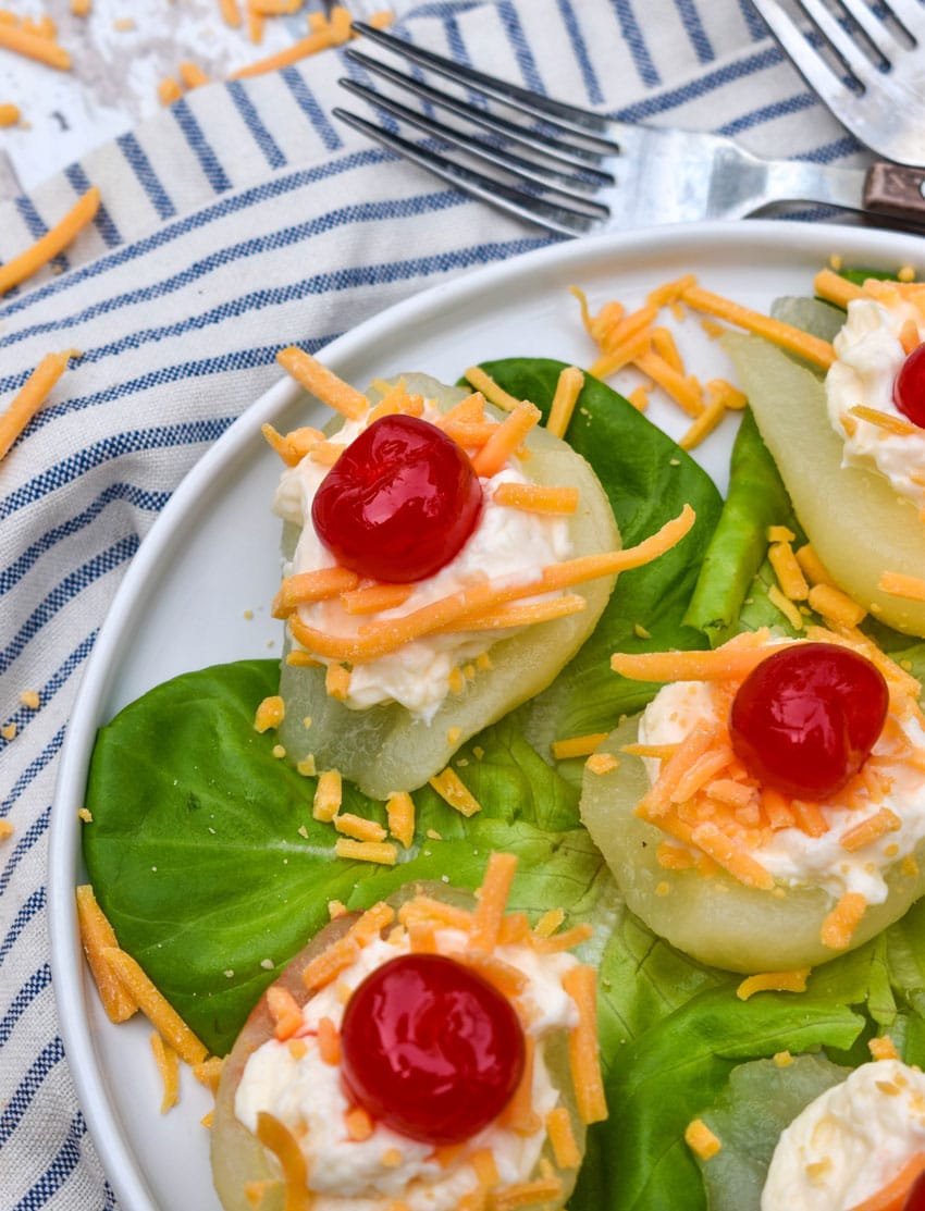 southern pear salad bites arranged over butter lettuce leaves on a white plate