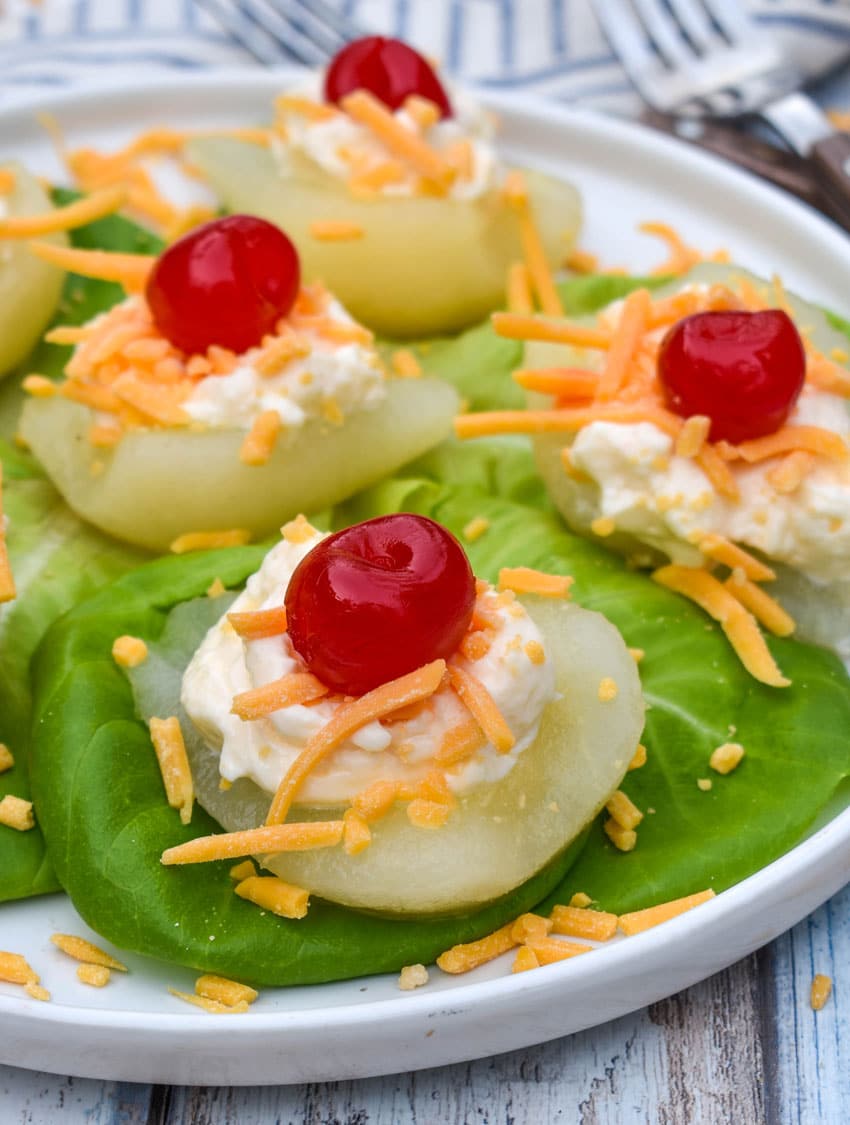 southern pear salad bites arranged over butter lettuce leaves on a white plate