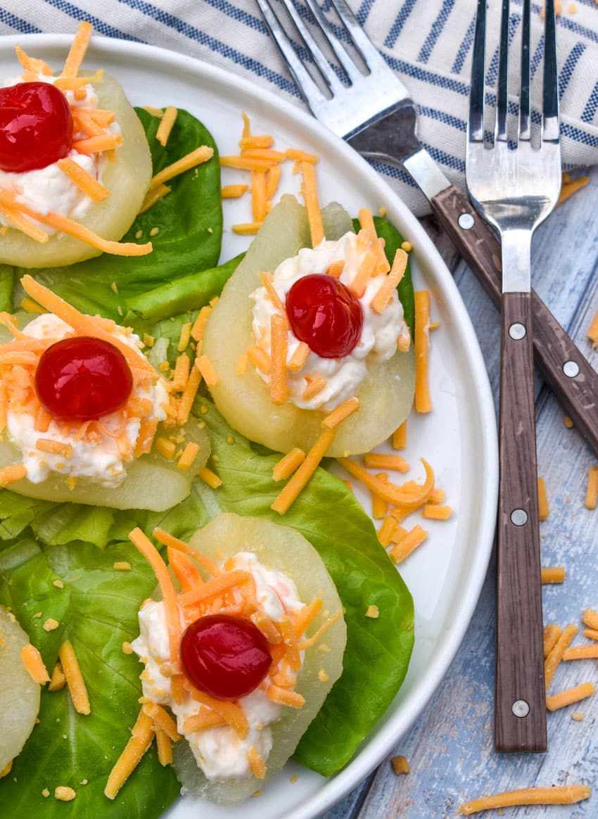 southern pear salad bites arranged over butter lettuce leaves on a white plate