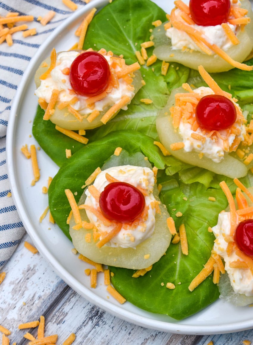 southern pear salad bites arranged over butter lettuce leaves on a white plate