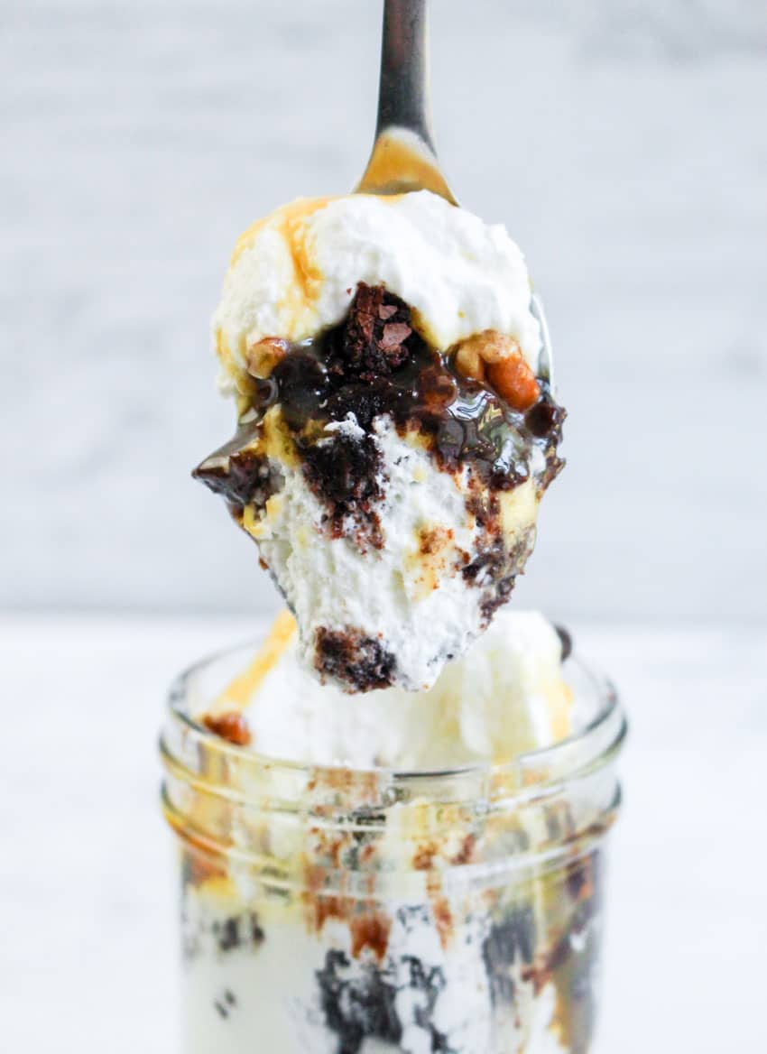 a spoon holding up a scoop of a homemade turtle brownie trifle