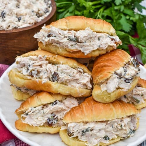 creamy tarragon chicken salad stuffed mini croissants stacked on a small white plate
