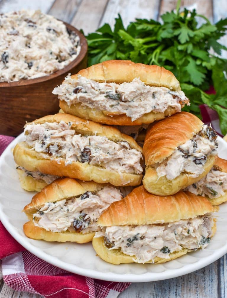creamy tarragon chicken salad stuffed mini croissants stacked on a small white plate