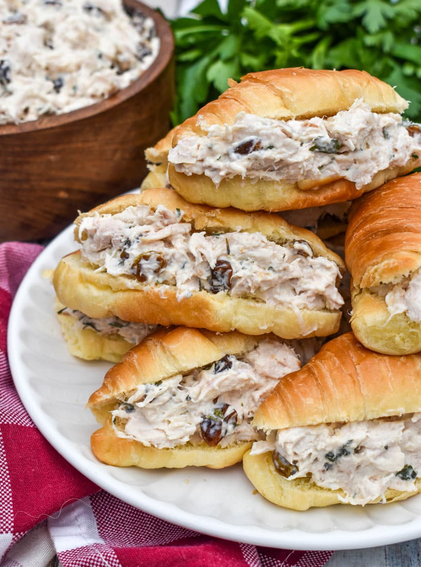 creamy tarragon chicken salad stuffed mini croissants stacked on a small white plate
