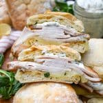 two halves of a copycat costco turkey provolone sandwich on a wooden cutting board