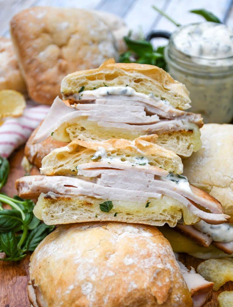 two halves of a copycat costco turkey provolone sandwich on a wooden cutting board