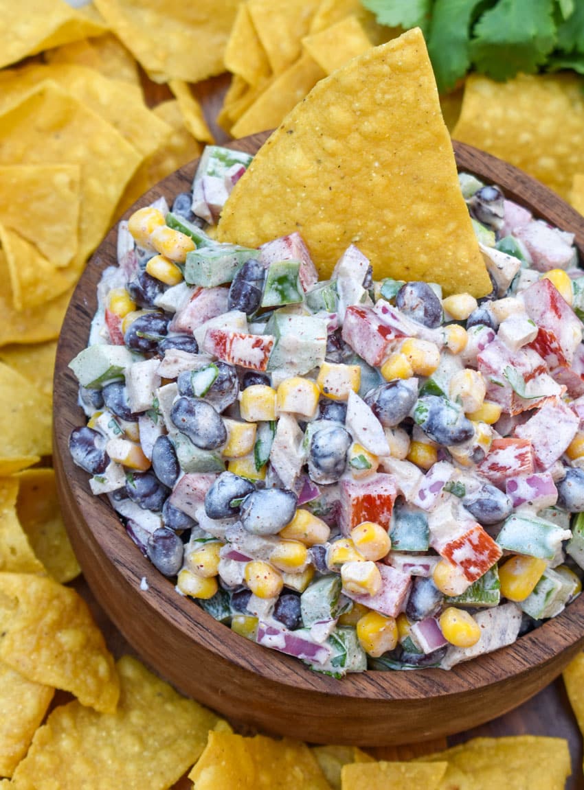 creamy black bean salsa in a wooden bowl surrounded by homemade tortilla chips