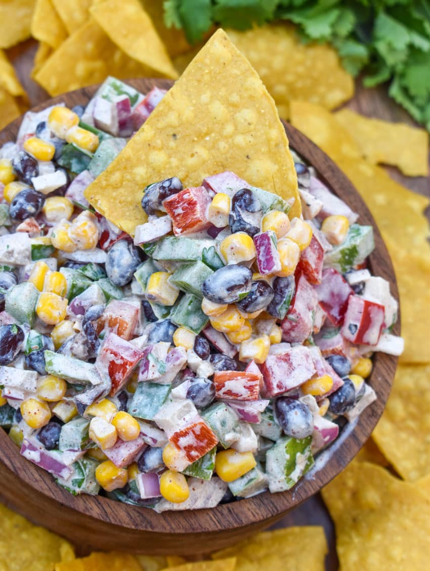 creamy black bean salsa in a wooden bowl surrounded by homemade tortilla chips