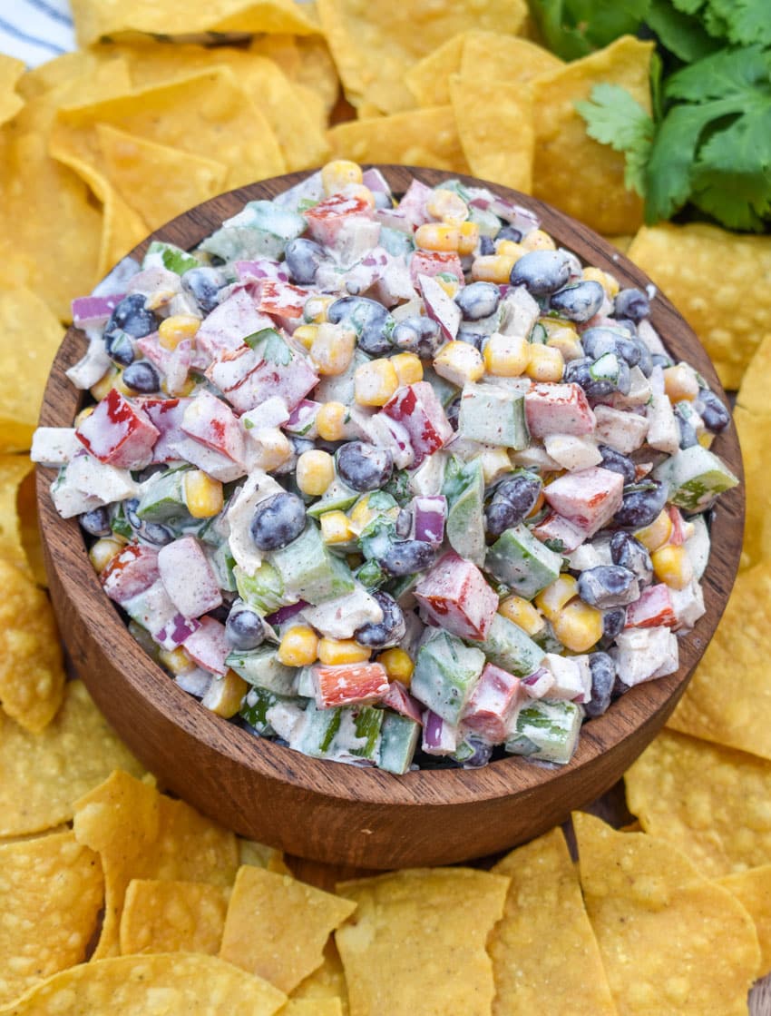 creamy black bean salsa in a wooden bowl surrounded by homemade tortilla chips