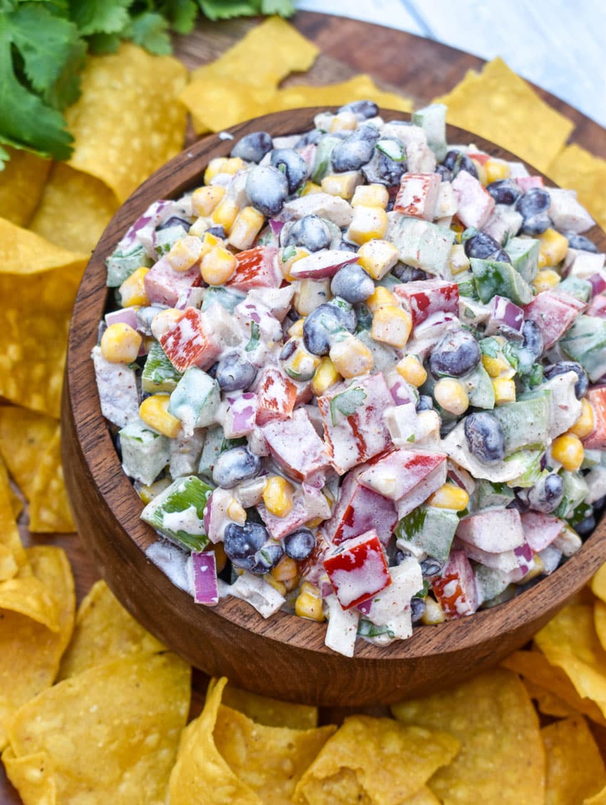 creamy black bean salsa in a wooden bowl surrounded by homemade tortilla chips