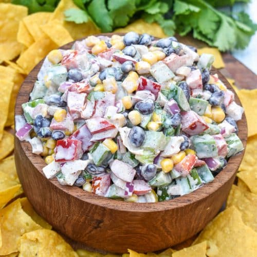creamy black bean salsa in a wooden bowl surrounded by homemade tortilla chips