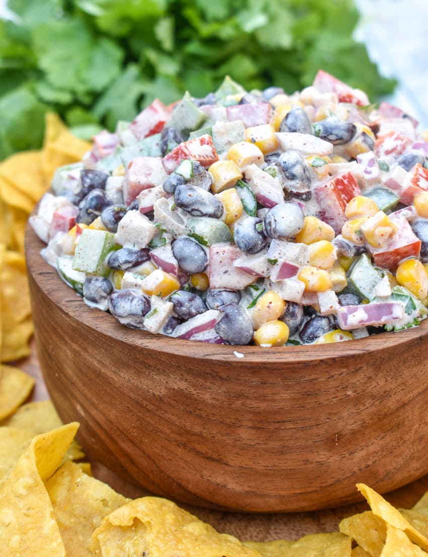 creamy black bean salsa in a wooden bowl surrounded by homemade tortilla chips