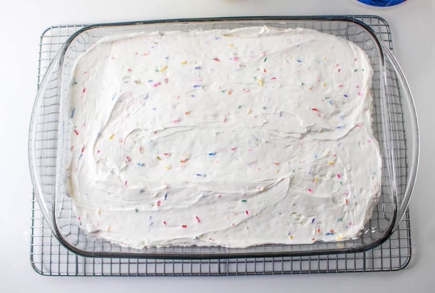 a funfetti frosting topped cake in a glass baking dish