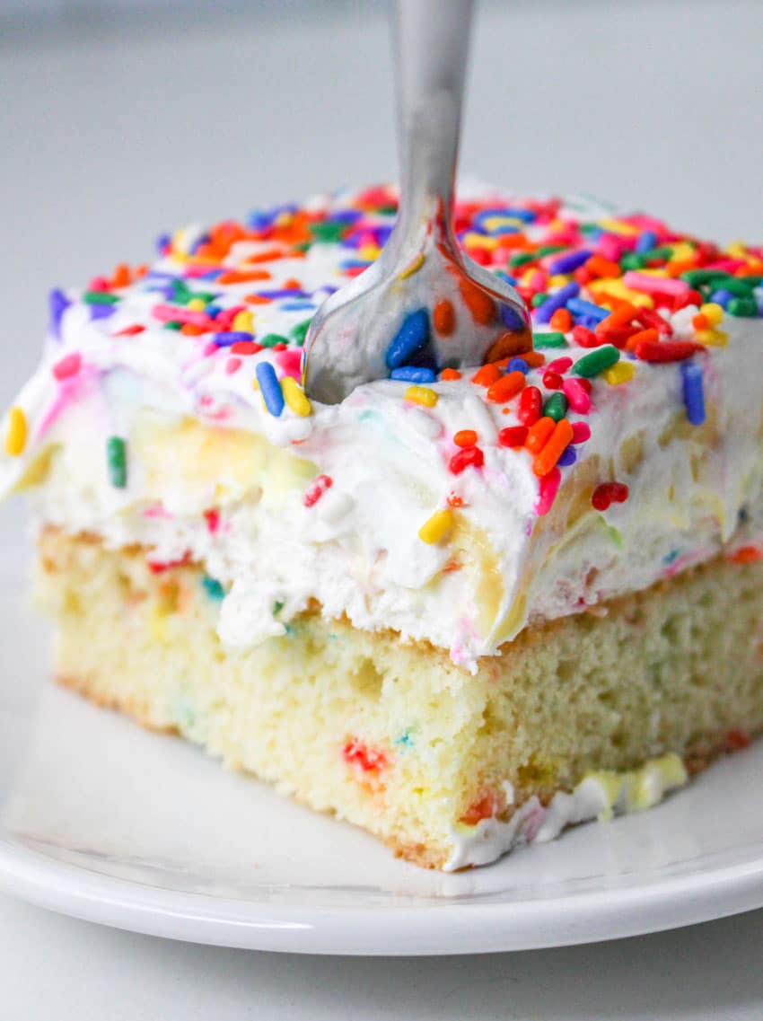 a slice of a layered funfetti cake dessert on a white plate