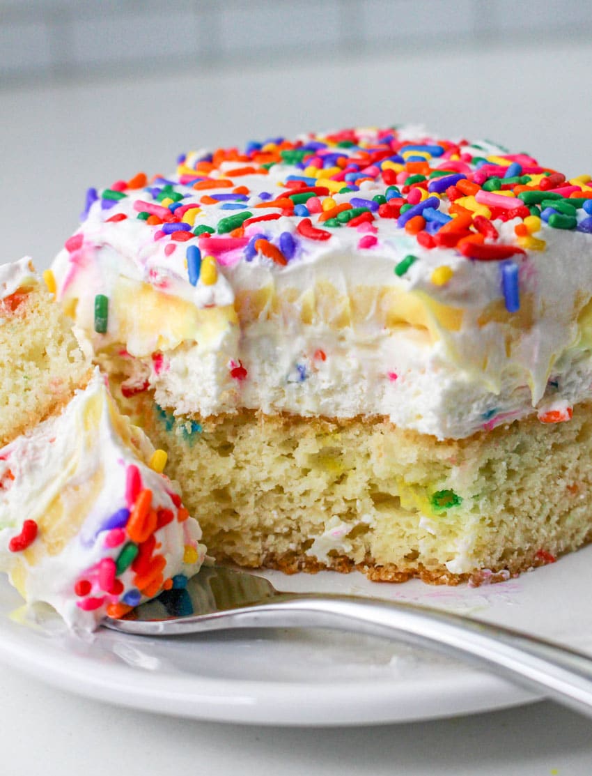 Layered Funfetti Dessert a slice of a layered funfetti cake dessert on a white plate