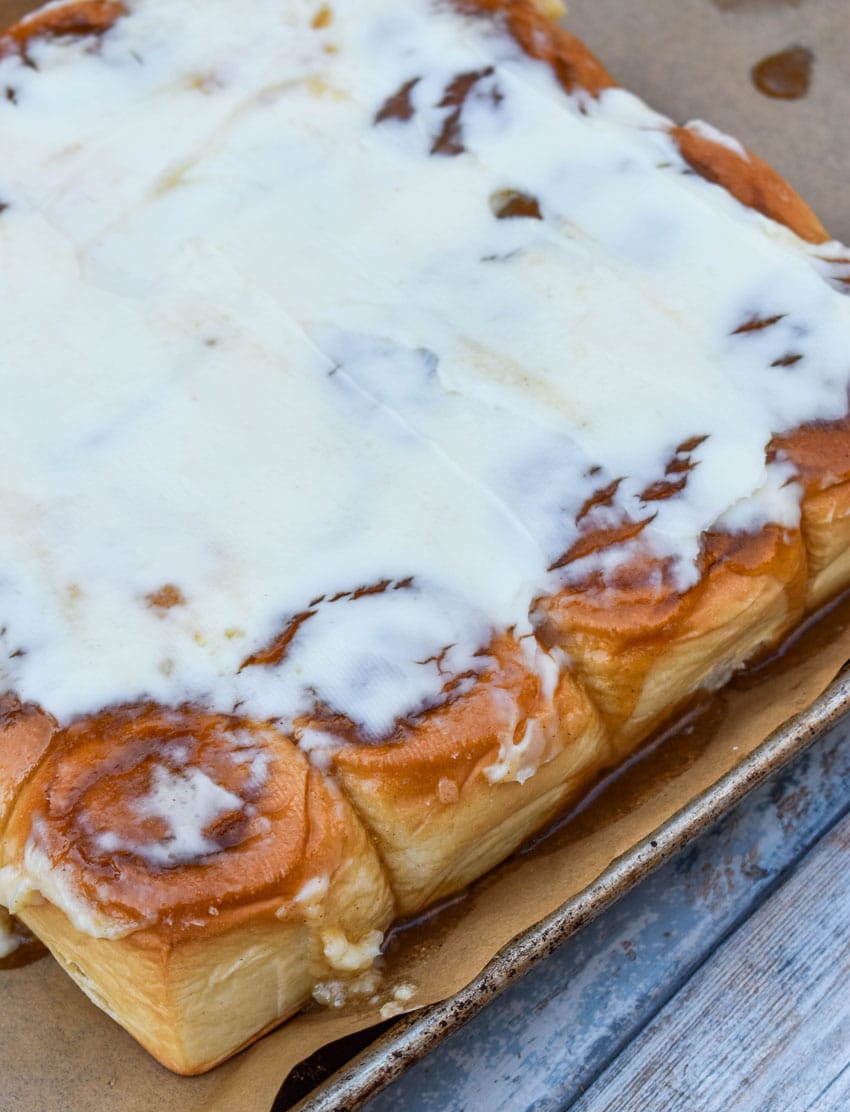 homemade cinnamon rolls made with hawaiian rolls on a parchment paper lined baking sheet