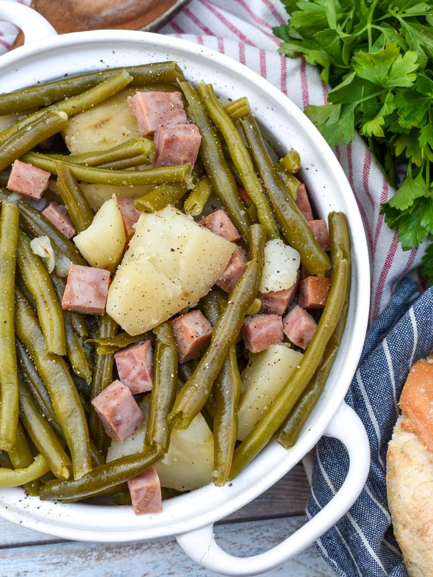 slow cooker green beans with ham in a white serving bowl
