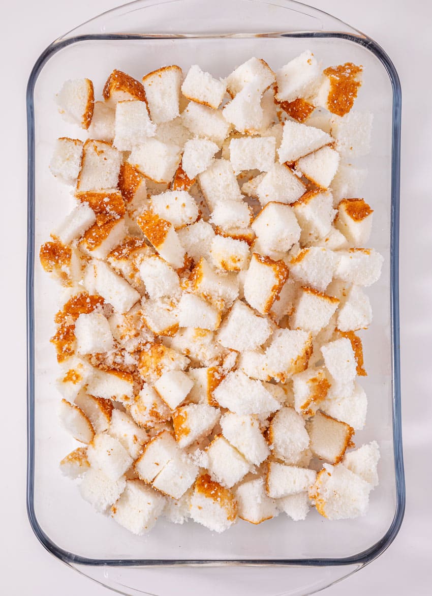 chunks of angel food cake spread out in the bottom of a glass baking dish