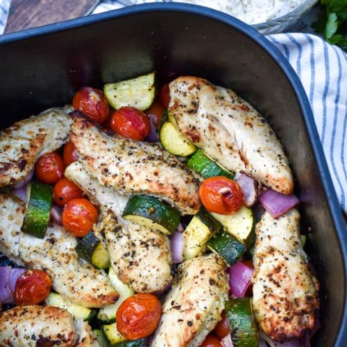 greek chicken and vegetables in the basket of an air fryer