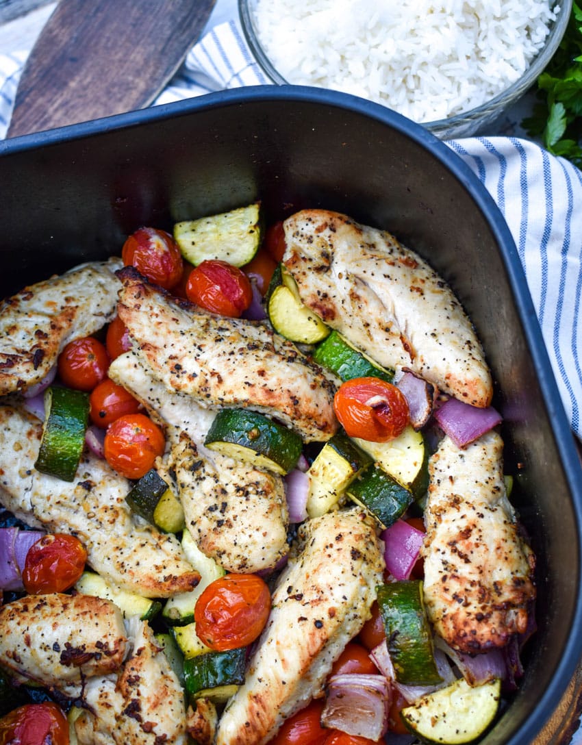 greek chicken and vegetables in the basket of an air fryer