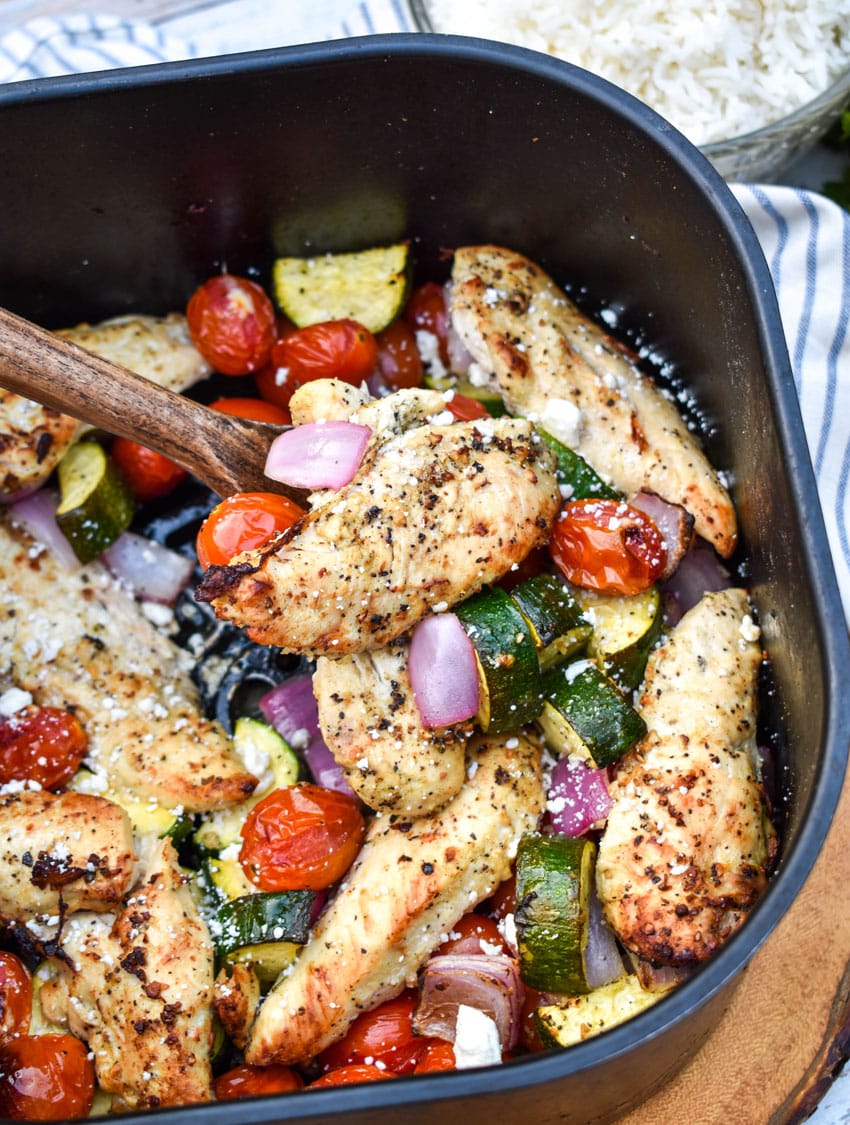greek chicken and vegetables in the basket of an air fryer