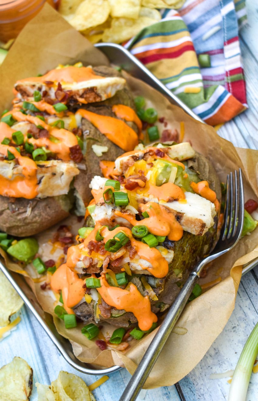 two homemade mcalister's chipotle chicken and bacon spuds on a parchment paper lined serving tray
