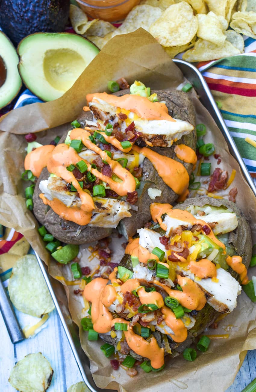 two homemade mcalister's chipotle chicken and bacon spuds on a parchment paper lined serving tray