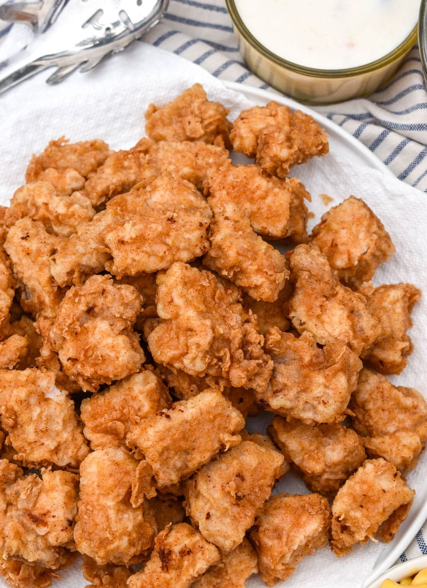 country fried pork nuggets draining on a paper towel lined plate