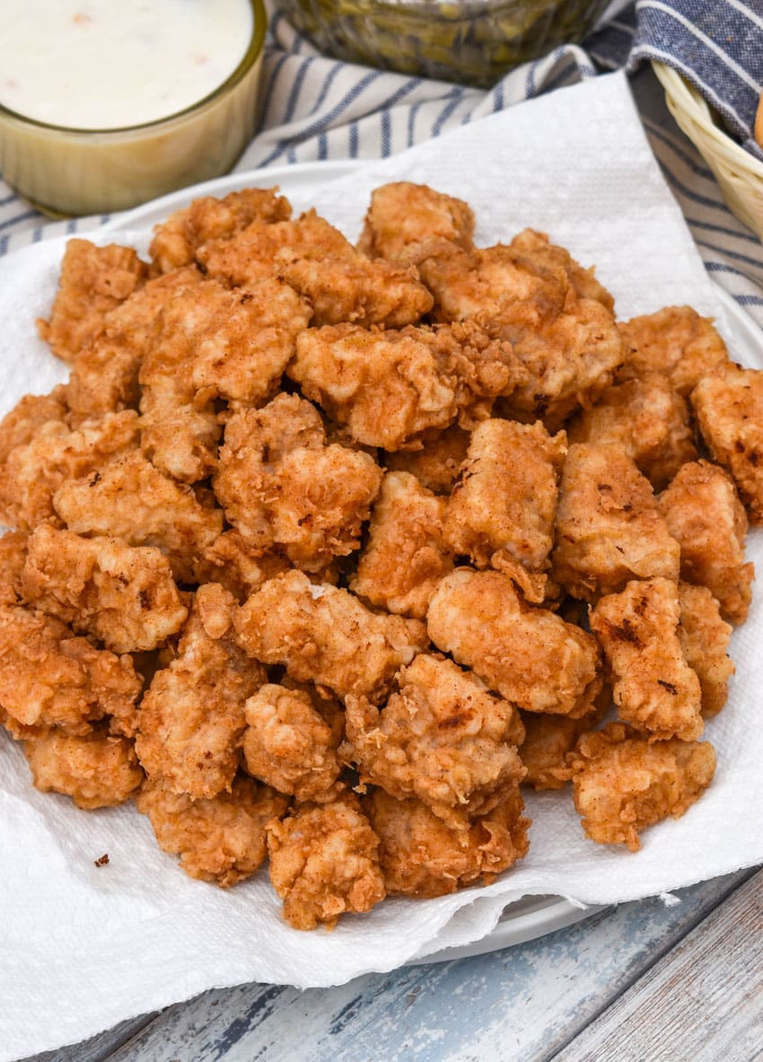 country fried pork nuggets draining on a paper towel lined plate