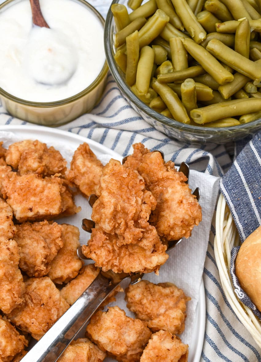 country fried pork nuggets draining on a paper towel lined plate
