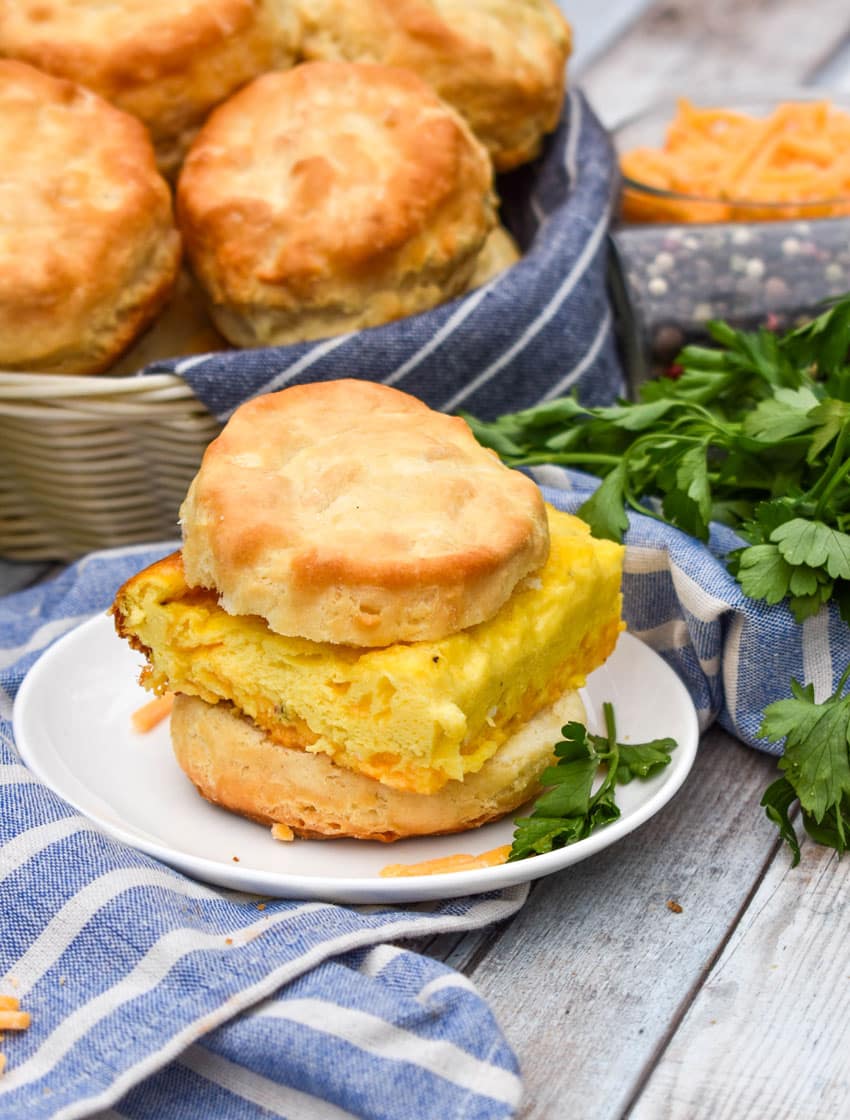 a slice of baked eggs on a biscuit on a small white plate