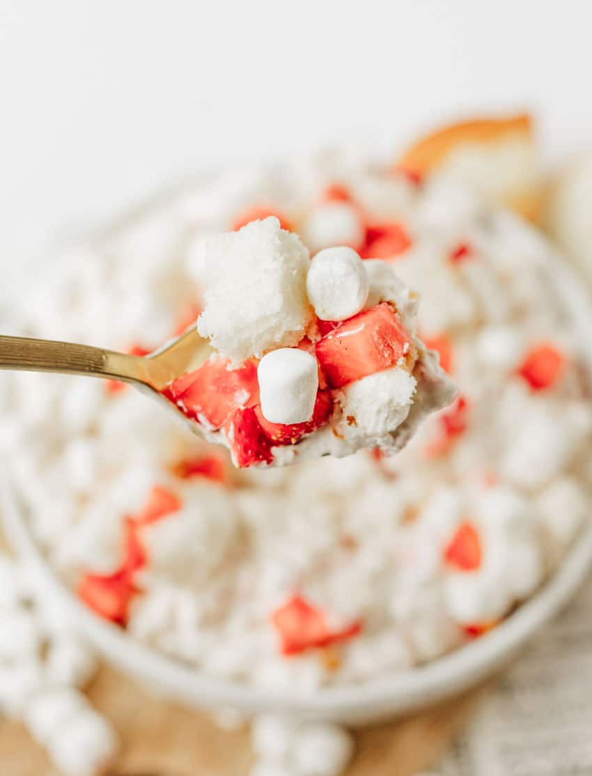 a spoon holding up a scoop of strawberry shortcake fluff salad