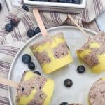 lemon blueberry pudding pops on a white plate with fresh blueberries on the side