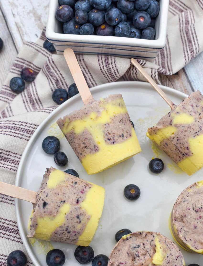 lemon blueberry pudding pops on a white plate with fresh blueberries on the side