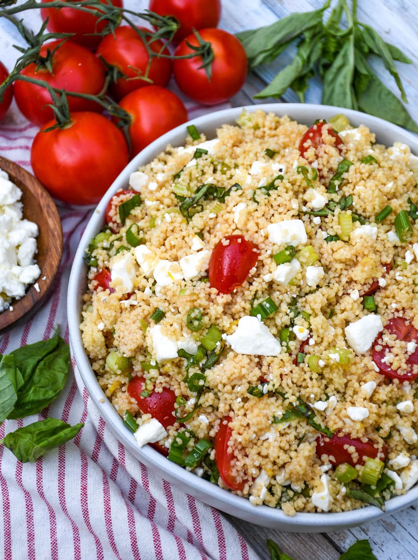 summer couscous salad in a gray serving bowl with fresh herbs on the side