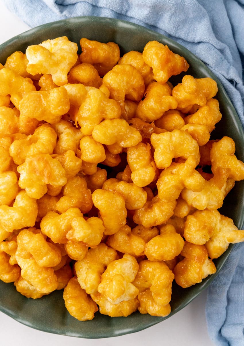 a close up of caramel coated puff corn snack in a green serving bowl