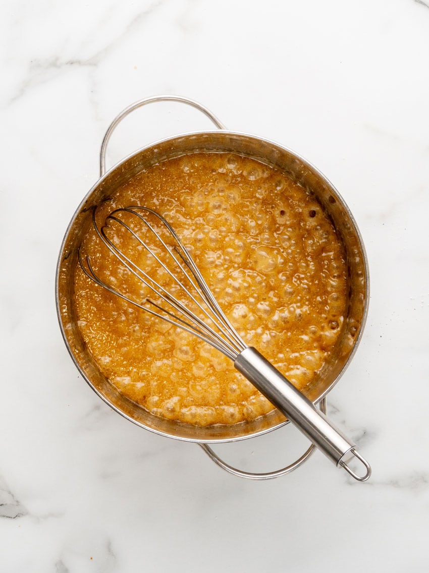homemade caramel sauce bubbling in a metal sauce pans
