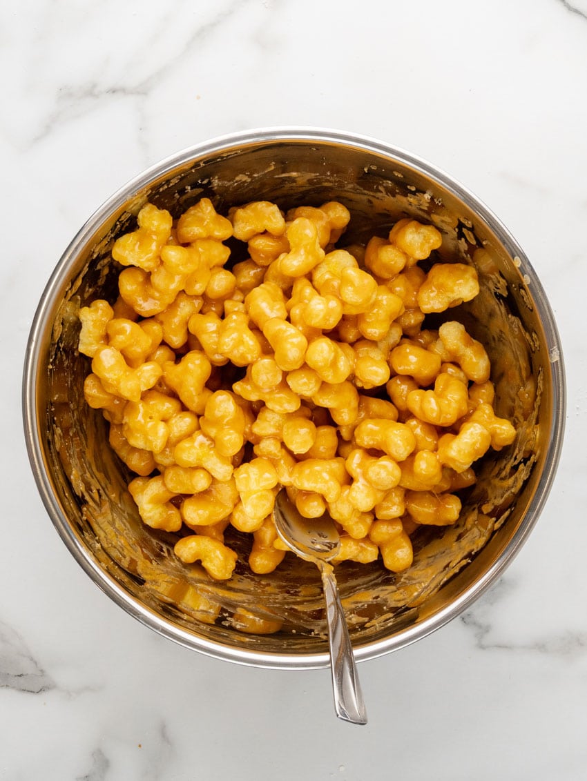 puff corn coated in a homemade caramel sauce in a metal mixing bowl